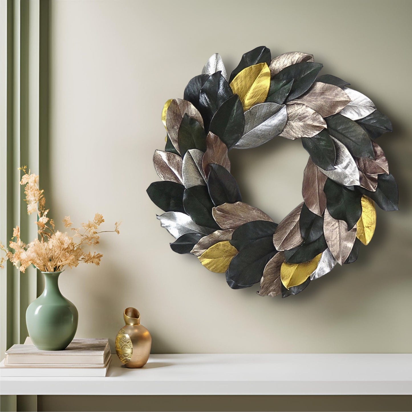 modern preserved magnolia wreath on a pastel green wall hanging above a white shelf with books and gold decors on it