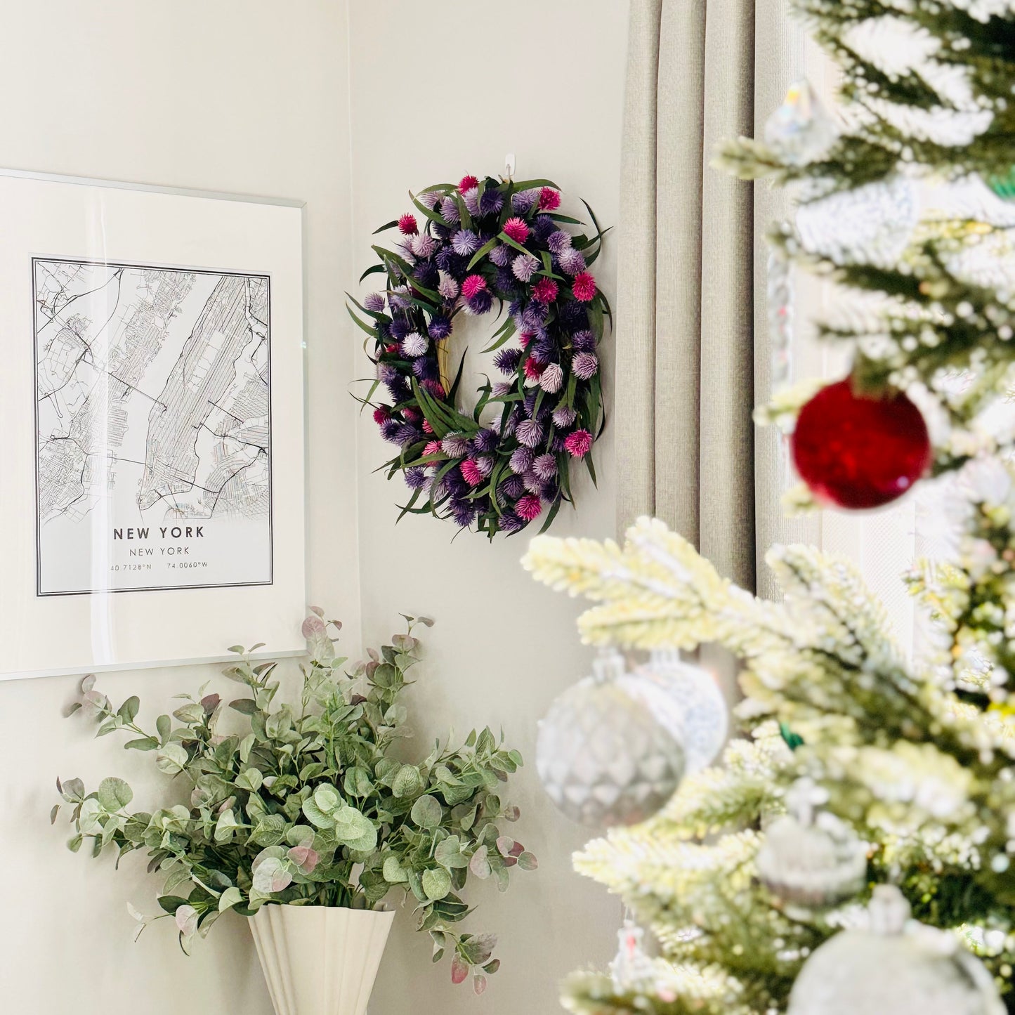 colorful preserved eucalyptus wreath decoration on the living room wall with christmas tree branches in the foreground