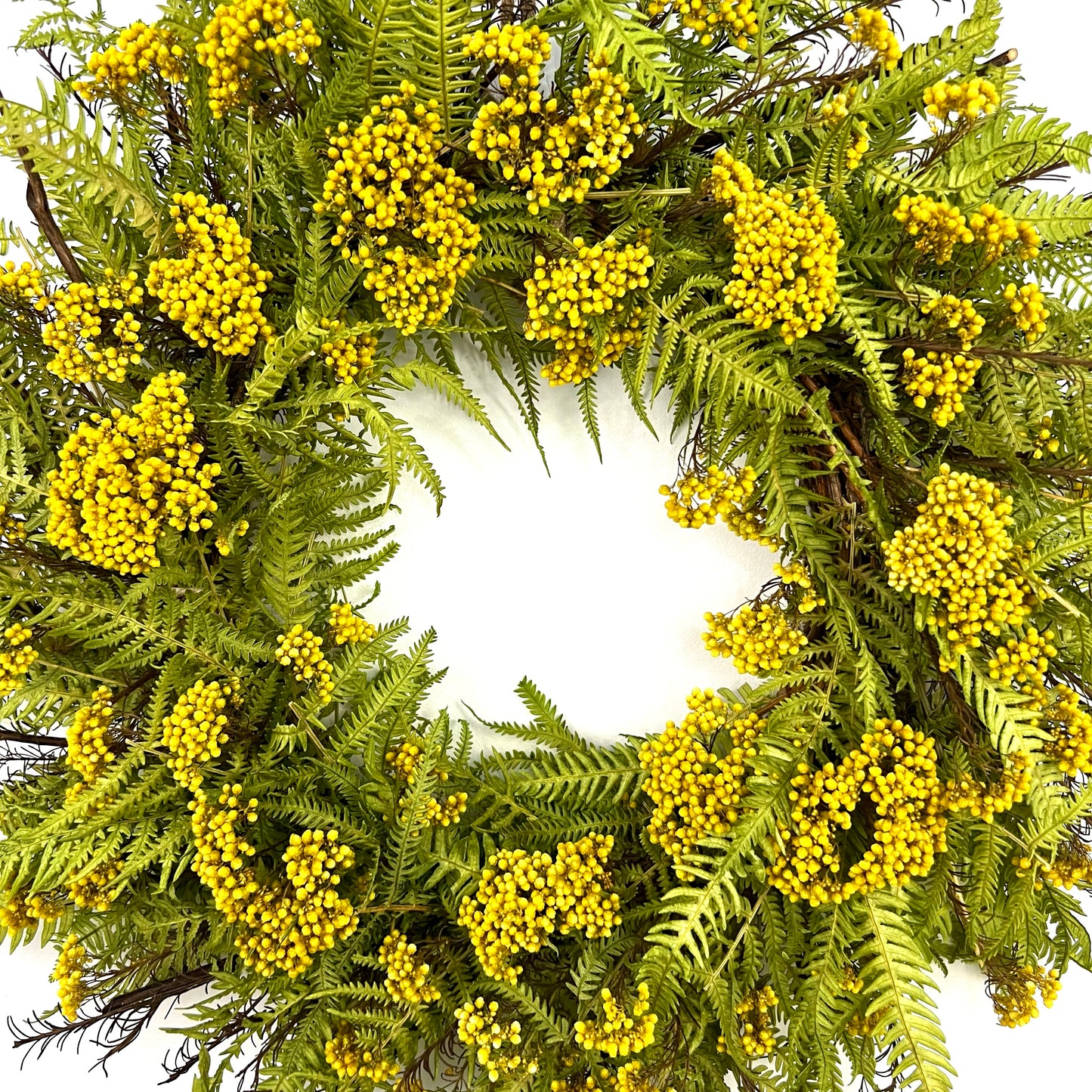 a closer look at the center of the spring wreath made from yellow rice flower and baby green fern