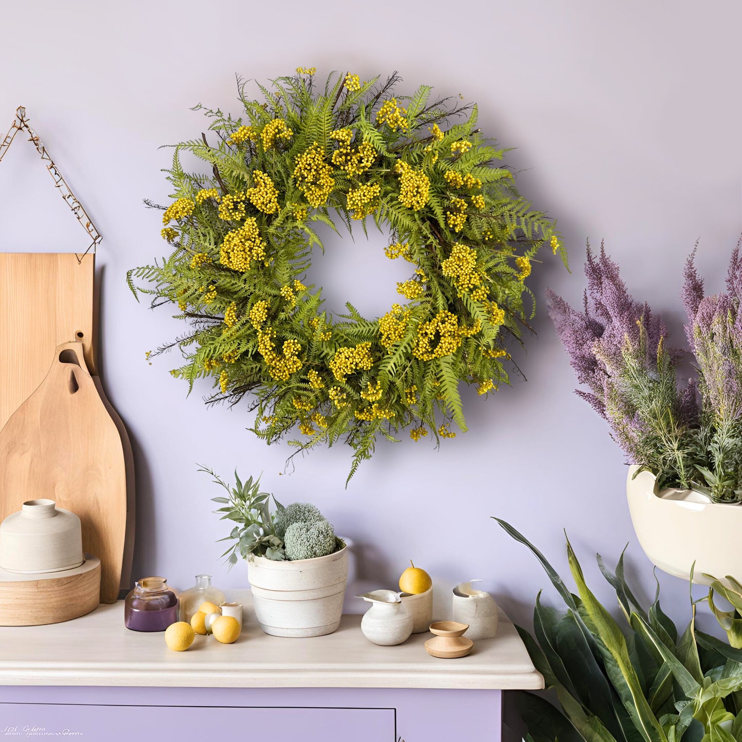 preserved spring wreath with fern on a light purple wall surrounded by greeneries as well as purple and yellow trinkets