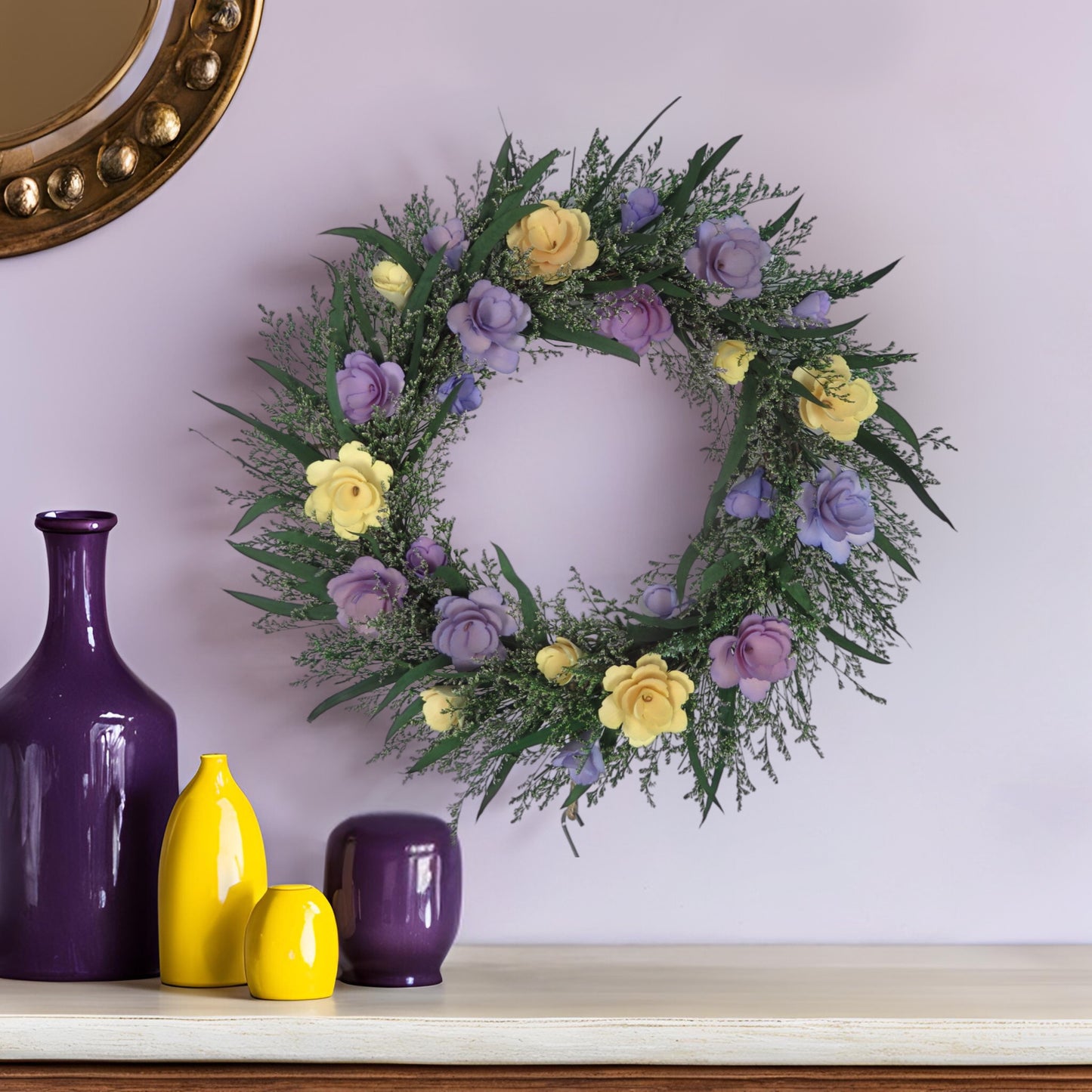 preserved spring summer wreath on a patel purple wall on top of a wooden table decorated with bright purple and yellow vases