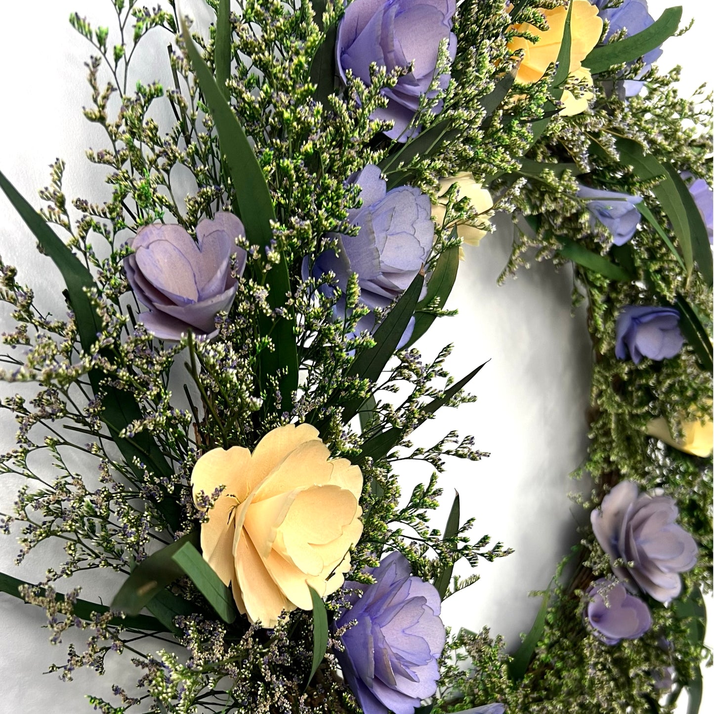 side view of the preserved wreath topped with eucalyptus leaves and caspia flowers