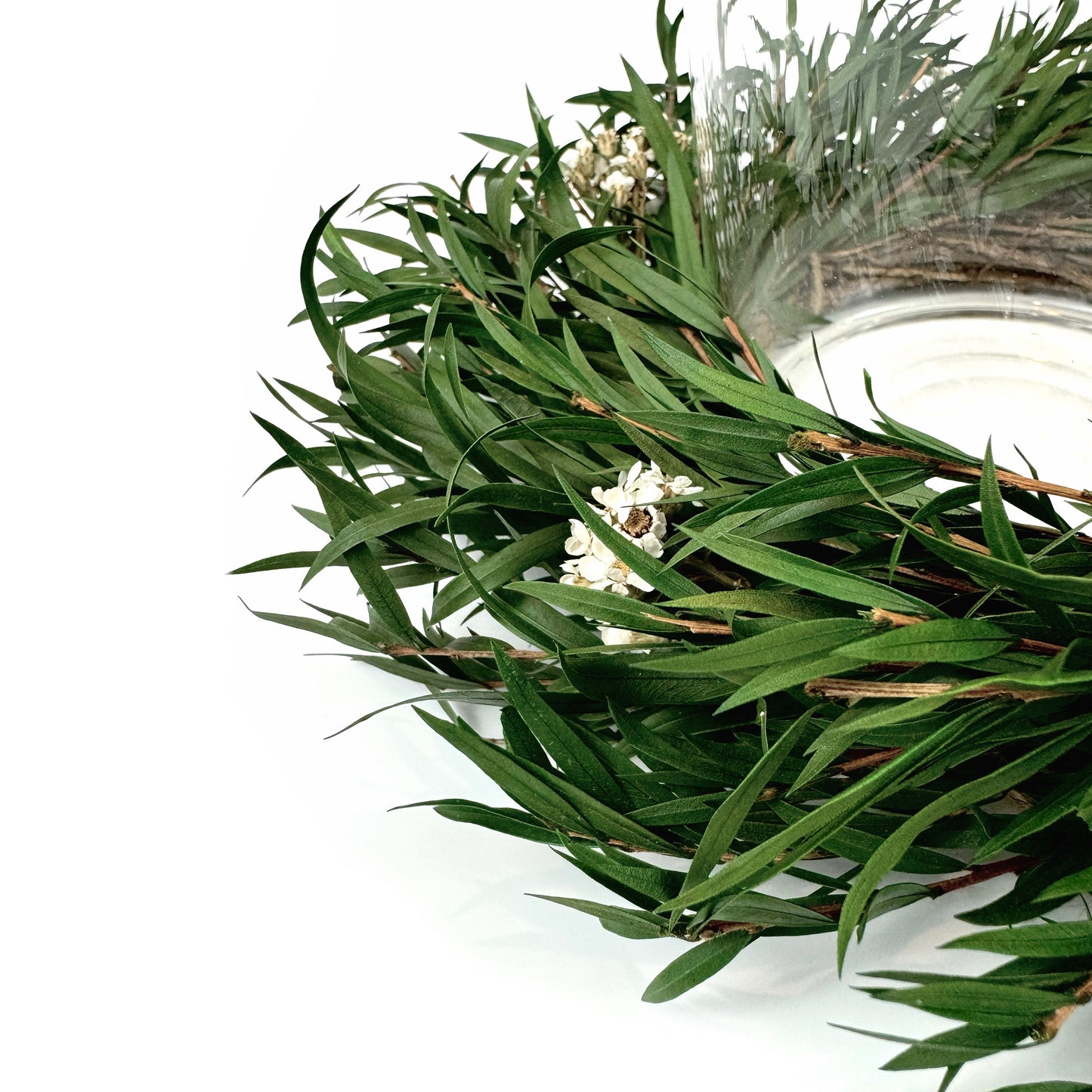 closeup look of minimalist candle ring wreath with greenery and white floral accents