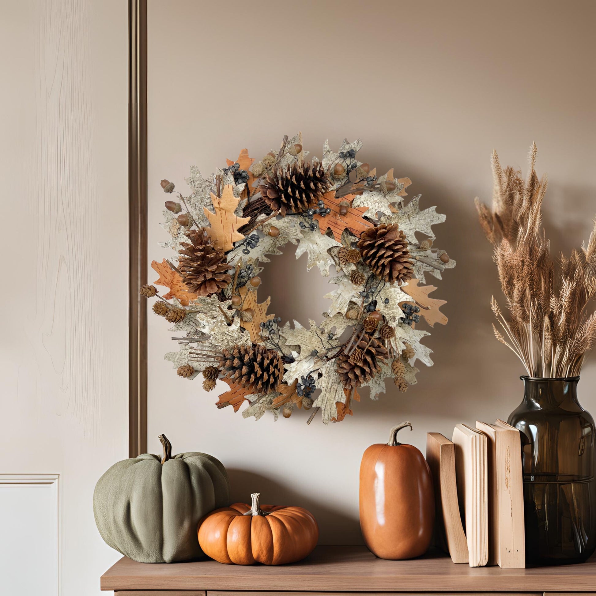 dried autumn wreath on the beige wall on top of a dresser with books and fall decorations on it