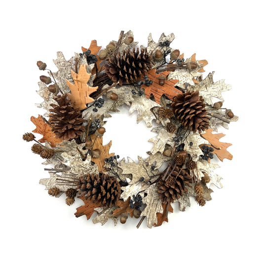 dried natural wreath with pinecones and acorns on top of off-white and brown birch barks