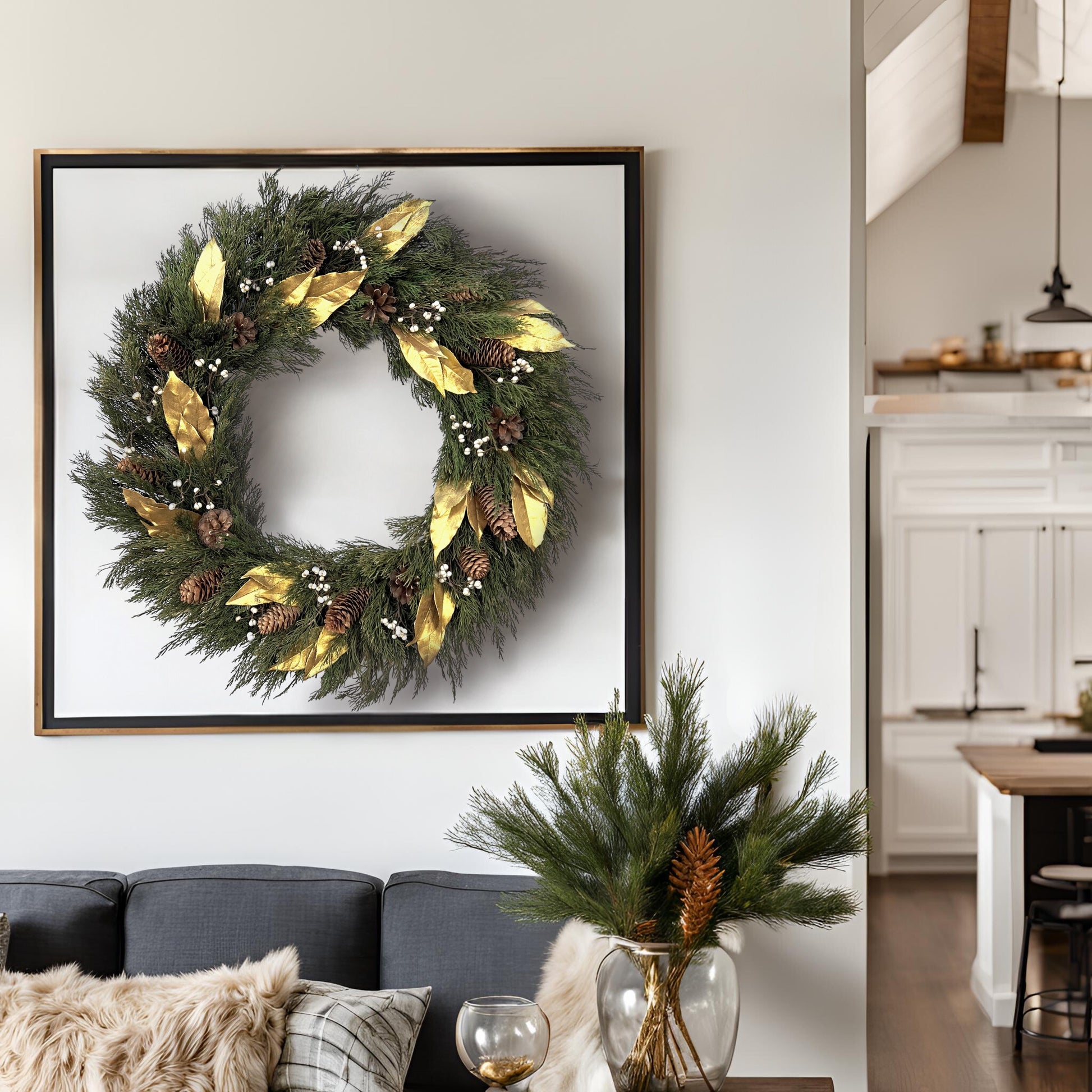 large luxurious christmas wreath hanging on the wall inside a black picture frame as a whole above a grey couch and greenery setup