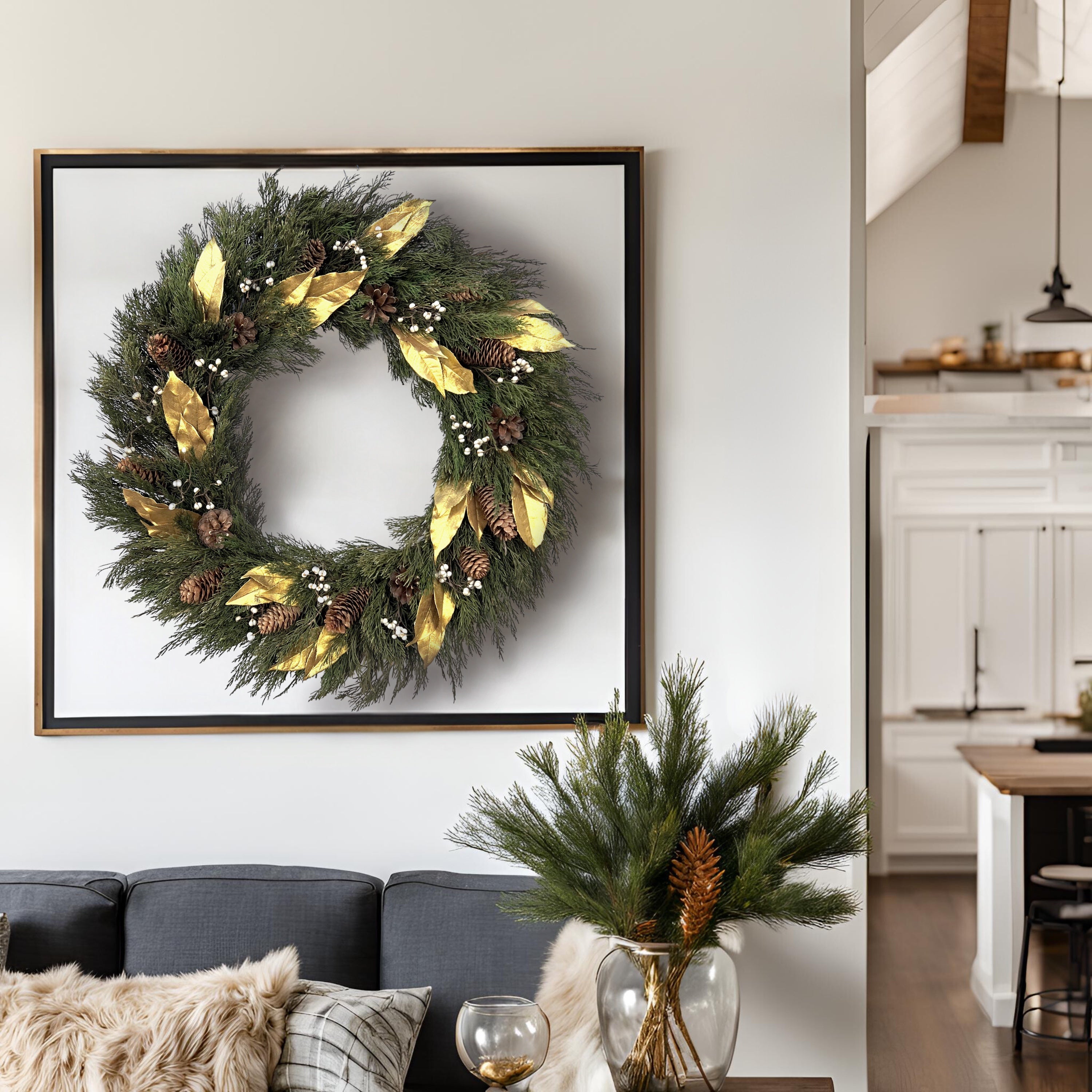large luxurious christmas wreath hanging on the wall inside a black picture frame as a whole above a grey couch and greenery setup