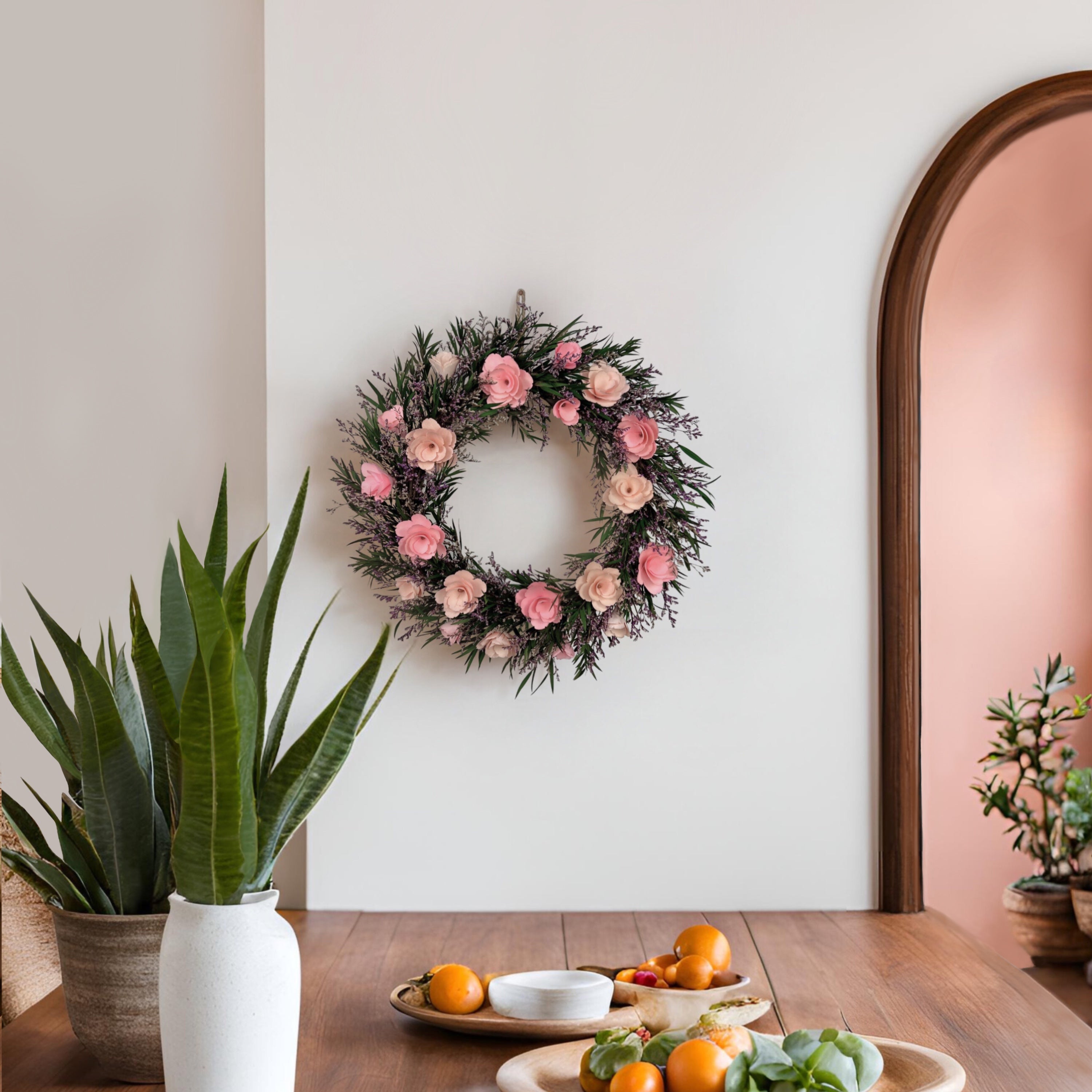 Floral wreath on a wall above a wooden table with plants and fruit