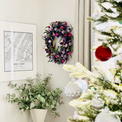 colorful preserved eucalyptus wreath decoration on the living room wall with christmas tree branches in the foreground