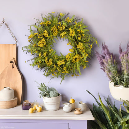 preserved spring wreath with fern on a light purple wall surrounded by greeneries as well as purple and yellow trinkets