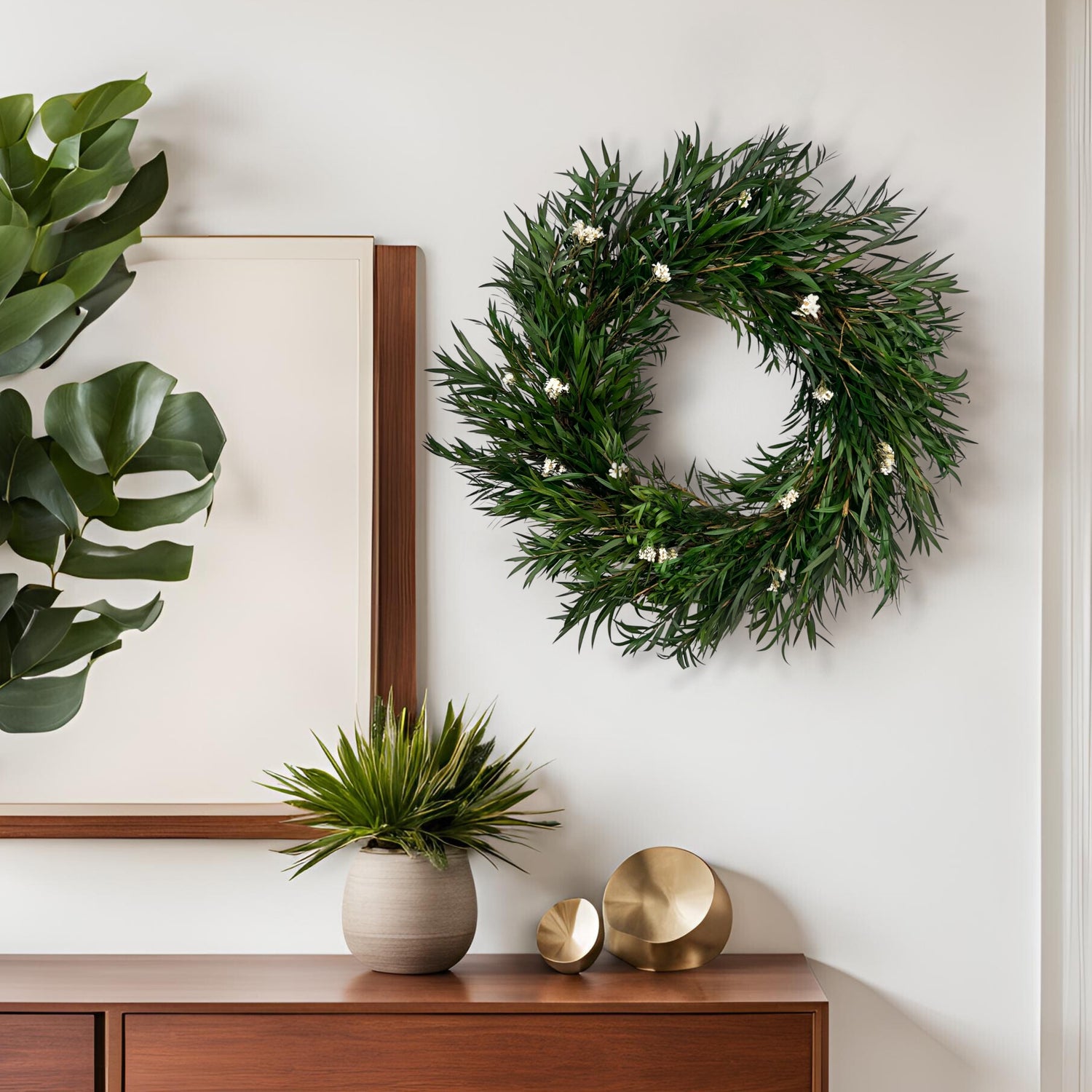 Green wreath on a wall above a wooden cabinet with decorative items
