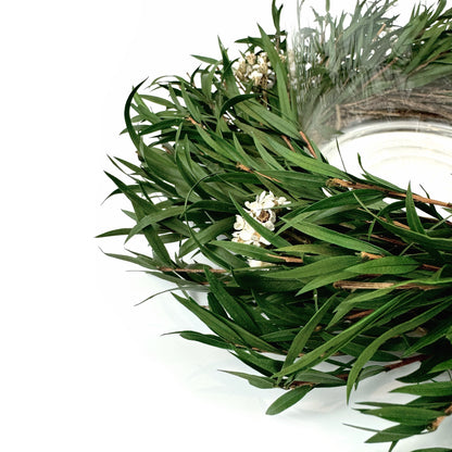closeup look of minimalist candle ring wreath with greenery and white floral accents