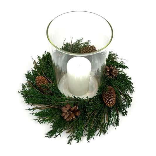Top view of preserved candle ring wreath with pinecones around a glass candle  holder cylinder